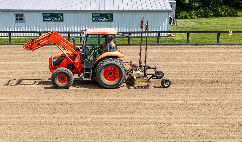 Arena contractor laser grading an outdoor arena with FootingFirst™ arena footing.
