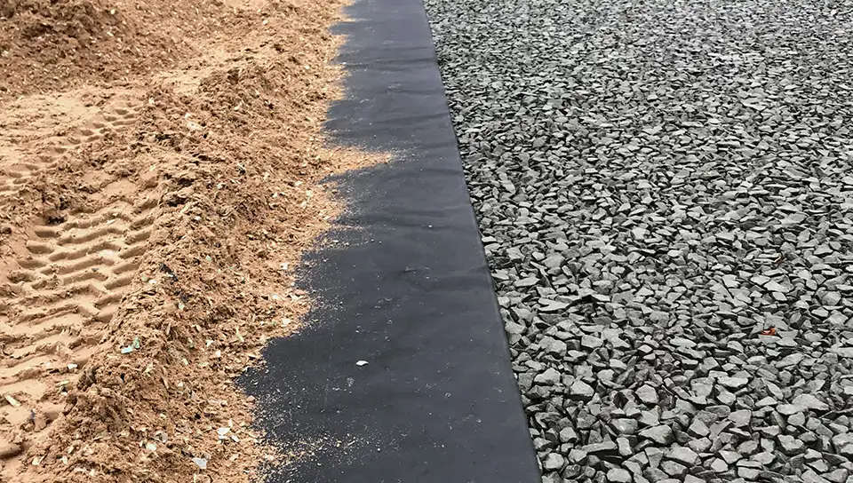 Filter fabric separation layer between arena base and footing